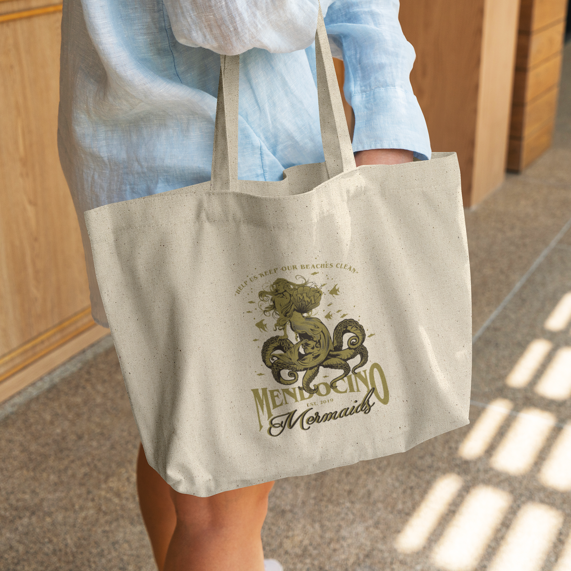 Mendocino_Mermaids_Tote_bag_CottonTote_L_WomanDigging_Mockup.png